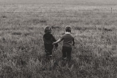 两个男孩走在绿色的草地
